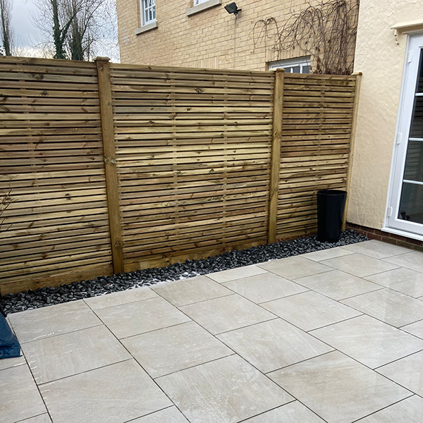 Image shows a garden fence and patio. Image depicts Thomas Charles Landscapes' fence installation expertise