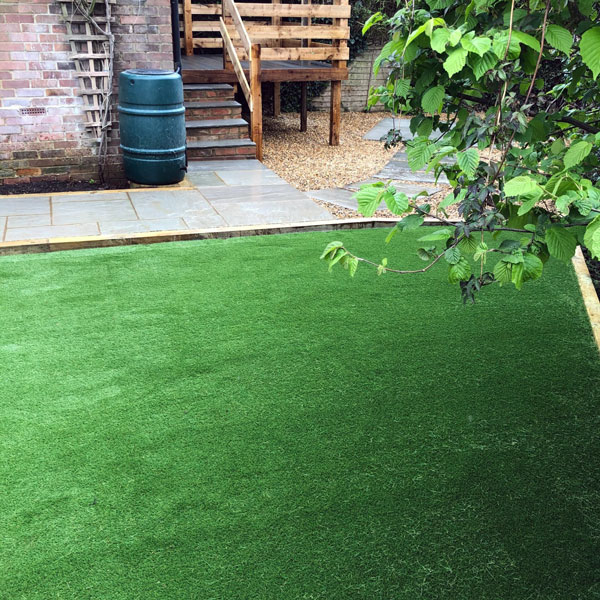 Image shows a newly laid lawn with patio, gravel and water butt  in the background. Image depicts Thomas Charles Landscapes' lawn and turf expertise