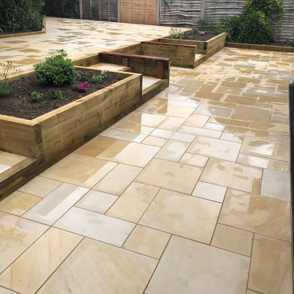 Image shows a newly laid patio with steps and raised beds incorporated. Image depicts Thomas Charles Landscapes patio installation expertise