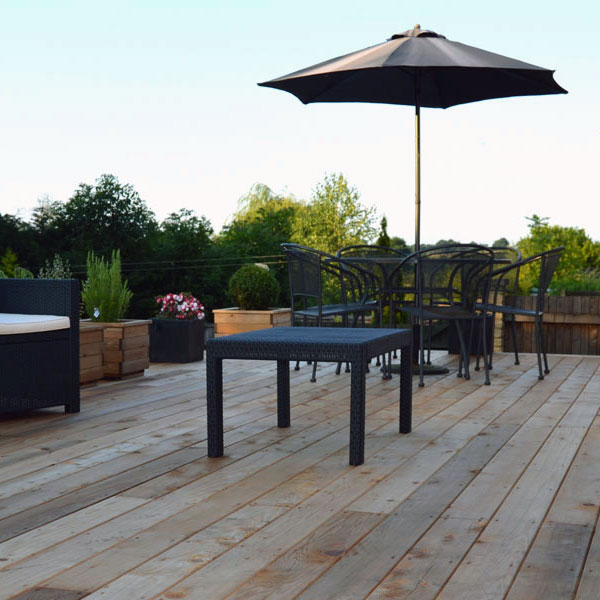 Images shows a wood deck with outdoor furniture on. Image depicts Thomas Charles Landscapes' decking installation expertise