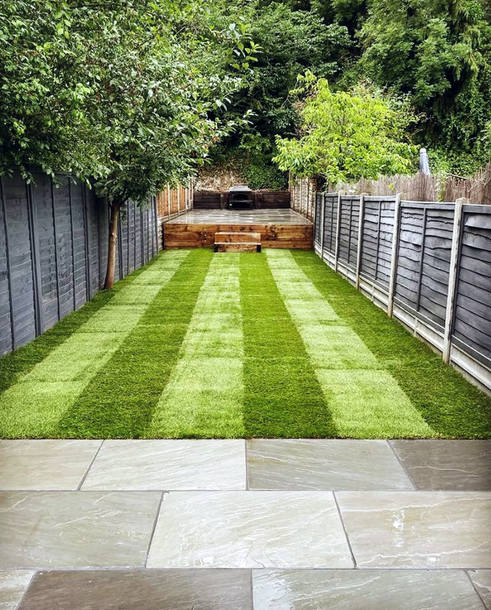 Image shows a newly landscaped garden with patio, lawn and raised seating area. 